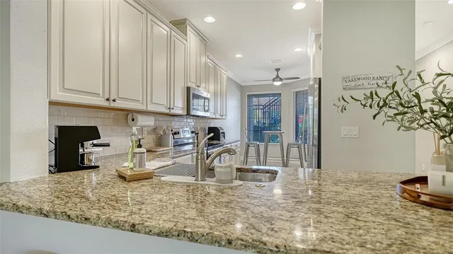 a kitchen with stainless steel appliances granite countertop a stove a sink and a microwave