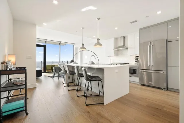 a kitchen with stainless steel appliances granite countertop a refrigerator a stove a sink dishwasher and a dining table with wooden floor