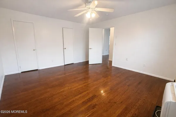 a view of empty room with wooden floor and fan