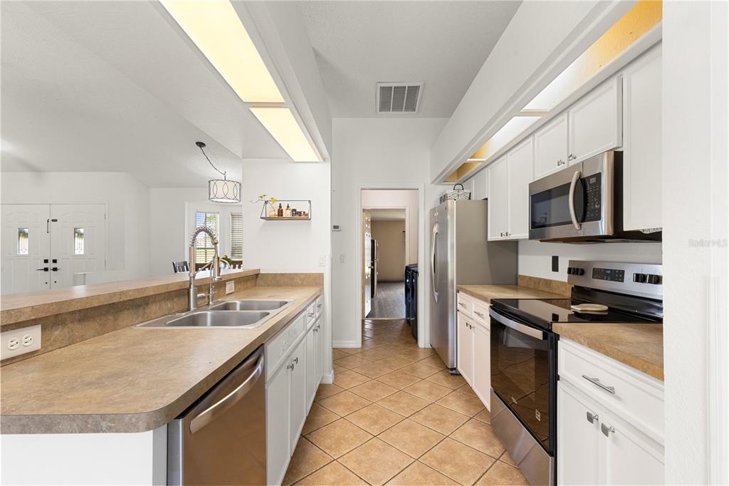 9917 Nelson Road Dade City, FL 33525 - Photo 16 of 40 a kitchen with stainless steel appliances granite countertop a sink a stove top oven a refrigerator cabinets and a dining table