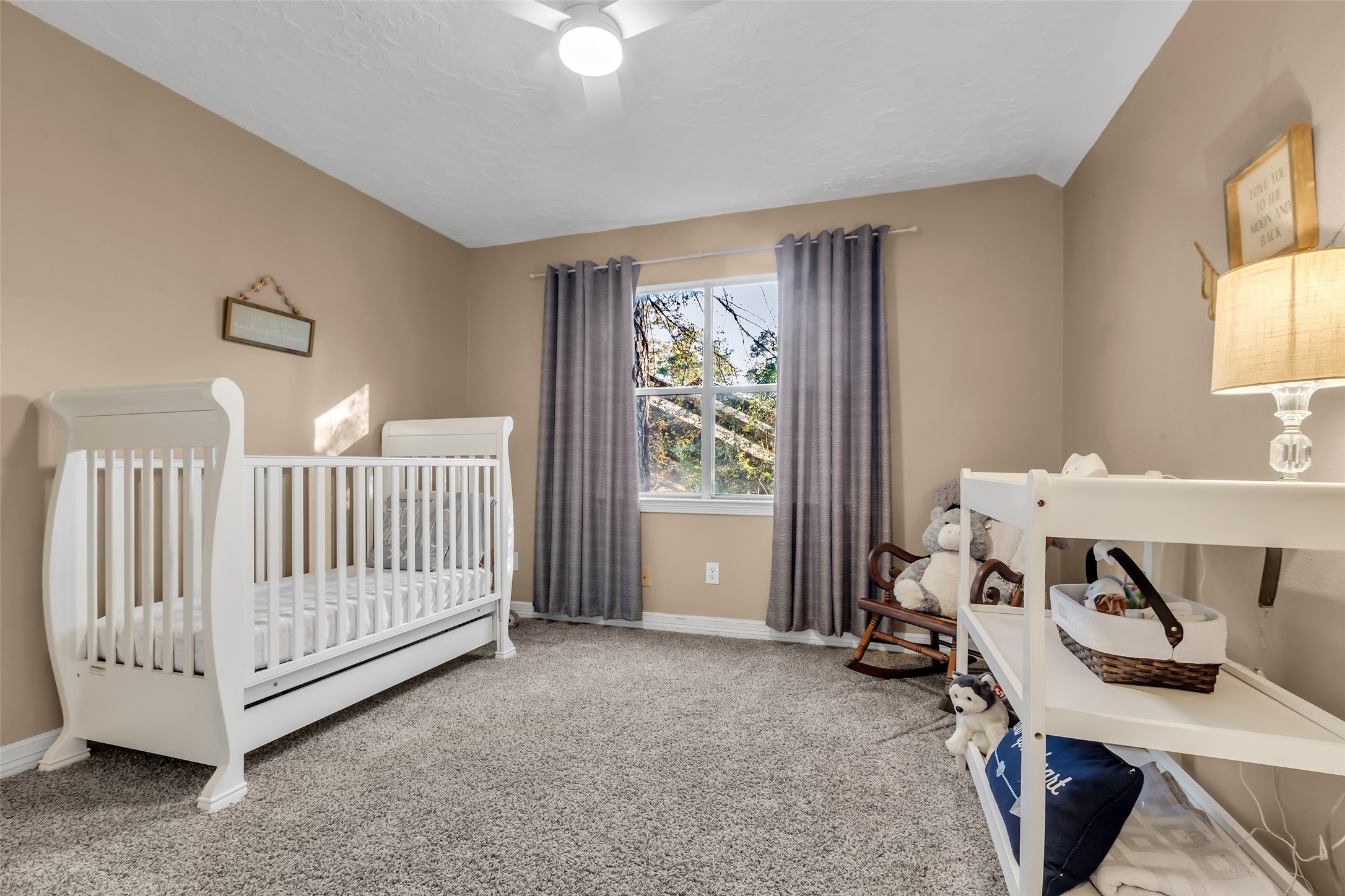 24102 Northcrest Drive Spring, TX 77389 - Photo 15 of 31 This inviting second upstairs bedroom features cozy carpeted floors, a bright window, and soothing neutral tones perfect for a nursery or child's retreat.
