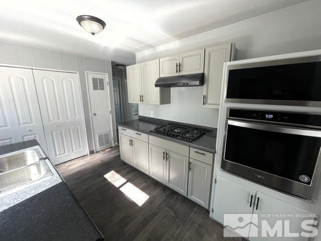 3625 Hummingbird Drive Reno, NV 89508 - Photo 5 of 18 a kitchen with stainless steel appliances a stove a microwave and white cabinets