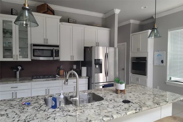 a kitchen with stainless steel appliances kitchen island granite countertop a refrigerator and a sink