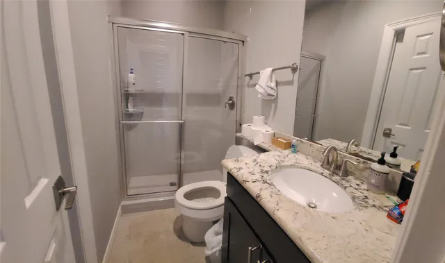 a bathroom with a granite countertop sink toilet and shower