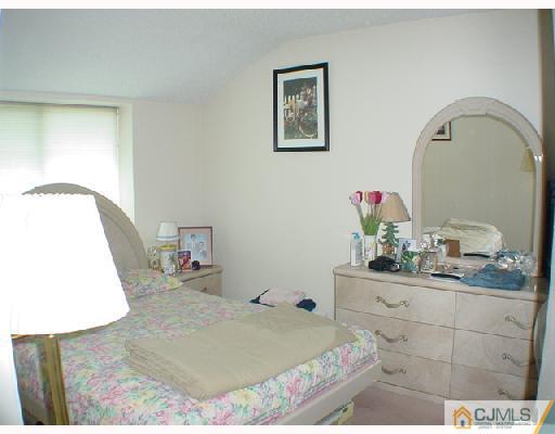 6201 Hana Road Edison, NJ 08817 - Photo 6 of 8 a bedroom with a bed and a mirror on dresser