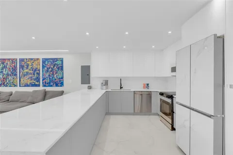 a large white kitchen with a stove a refrigerator and a sink