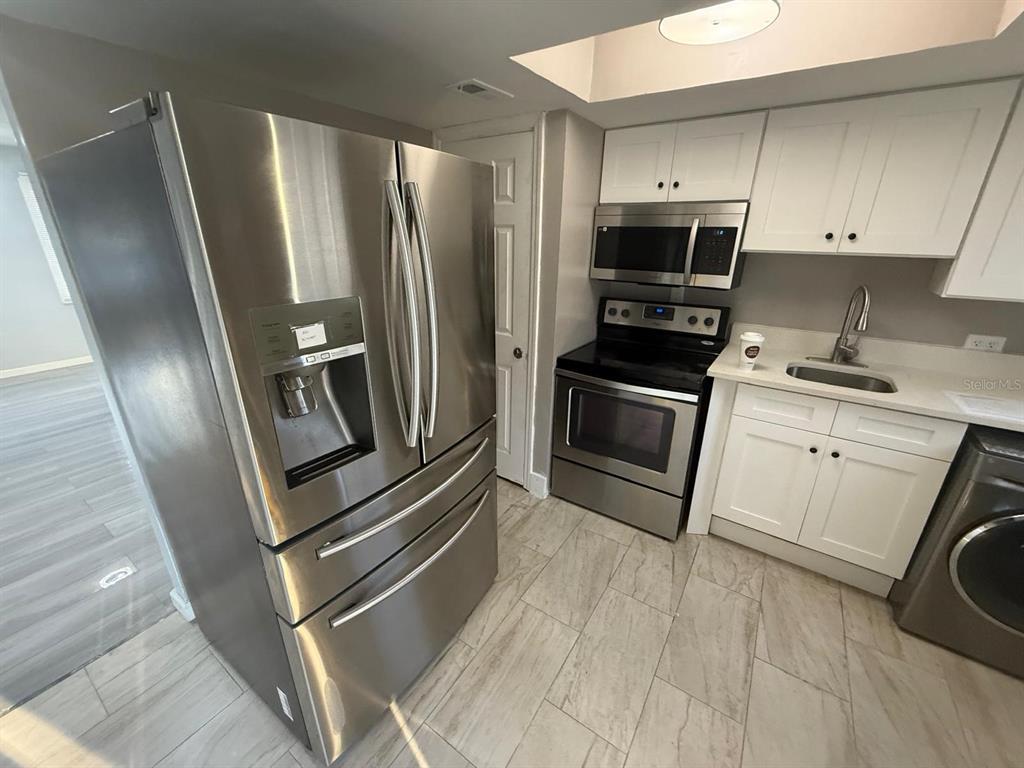 2787 L B McLeod Road, Unit 2787A Orlando, FL 32805 - Photo 9 of 34 a kitchen with stainless steel appliances granite countertop a refrigerator microwave and sink