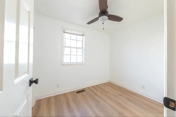 an empty room with a window and a ceiling fan