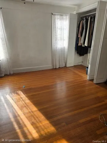 a view of an empty room with wooden floor and closet