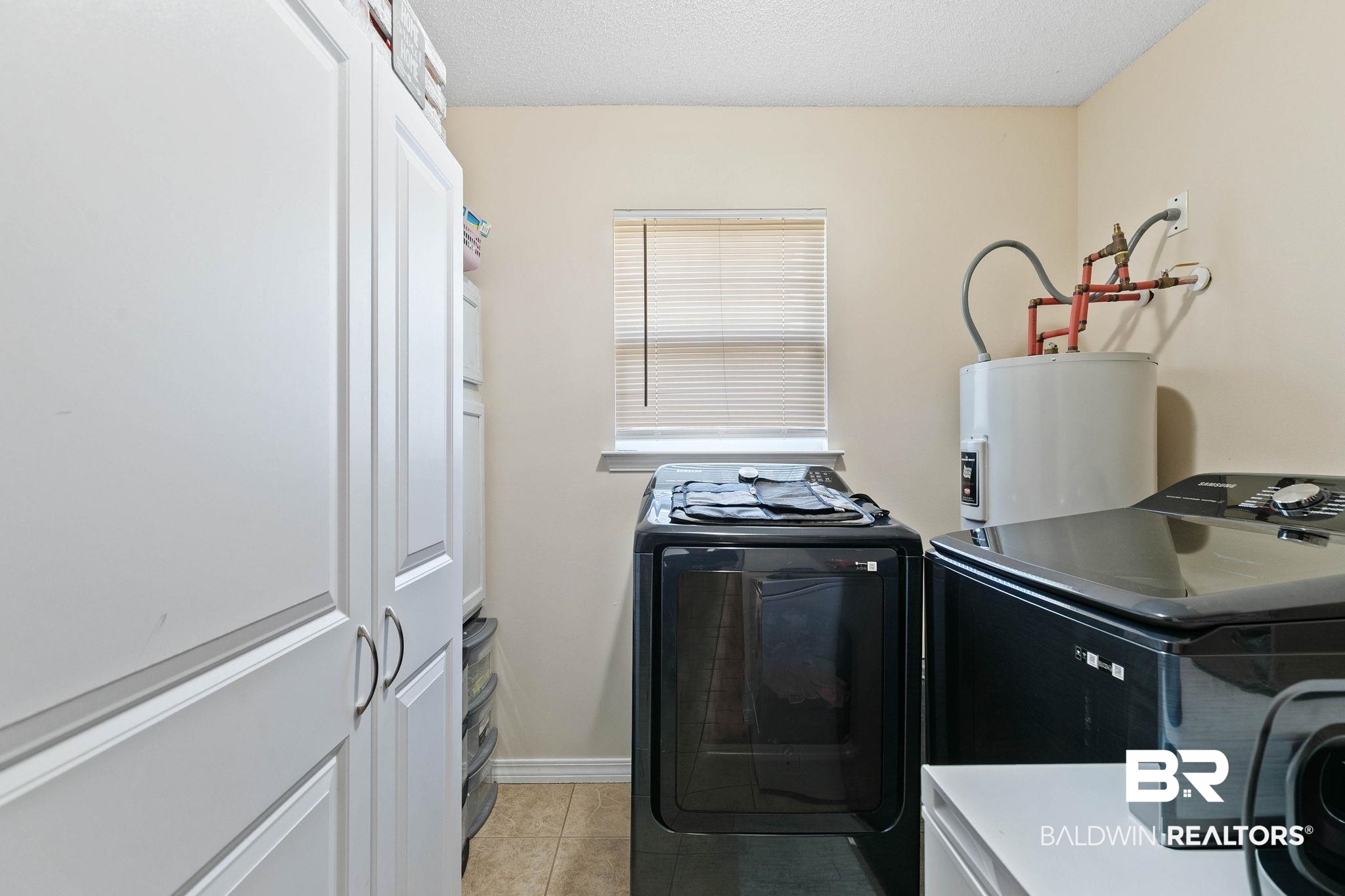 55750 Lottie Road Perdido, AL 36562 - Photo 42 of 84 Laundry area featuring a textured ceiling, washer and clothes dryer, electric water heater, and light tile patterned flooring