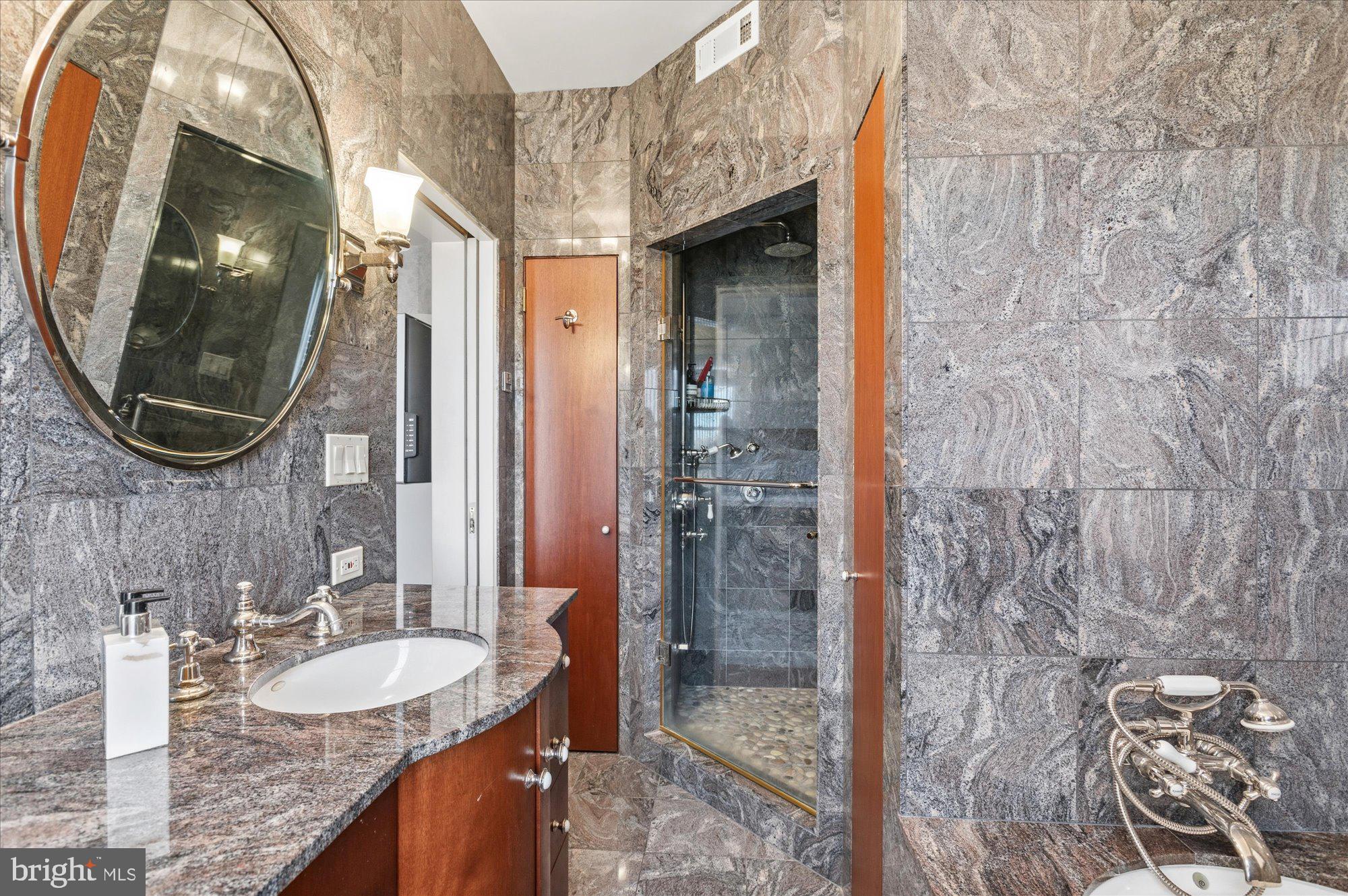 2101 Connecticut Avenue Northwest, Unit 78 Washington, DC 20009 - Photo 23 of 53 a bathroom with a granite countertop shower a mirror and sink