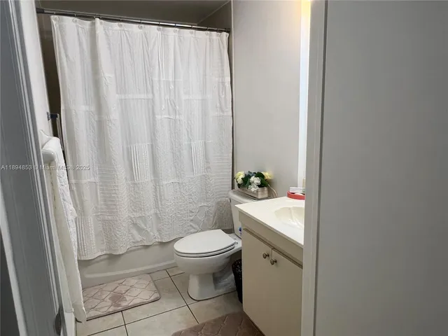 a bathroom with a sink a toilet and shower curtain