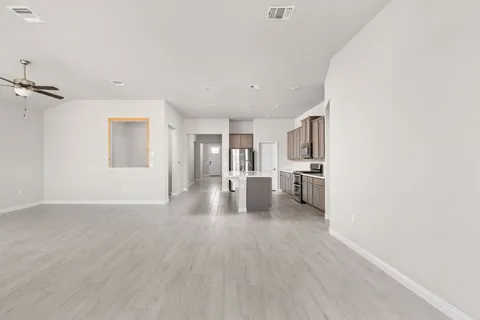 a big room with wooden floor and a kitchen
