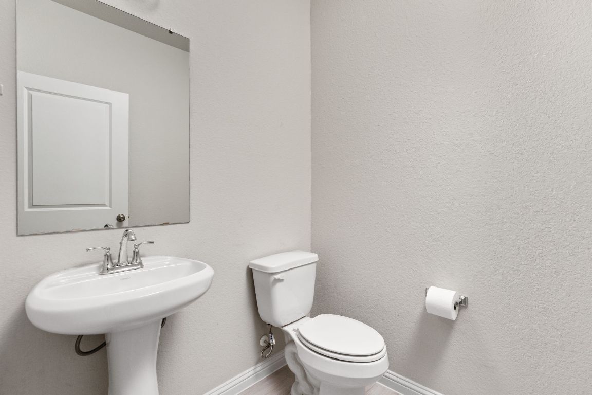 8408 Orizzonte Street Austin, TX 78744 - Photo 21 of 31 a bathroom with a toilet sink and mirror