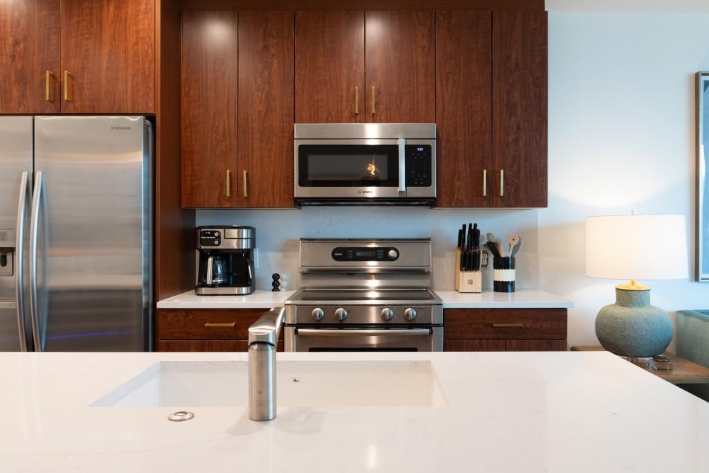 1080 Peachtree Street Northeast, Unit 1906 Atlanta, GA 30309 - Photo 6 of 46 a kitchen with stainless steel appliances kitchen island granite countertop a cabinets and a stove top oven