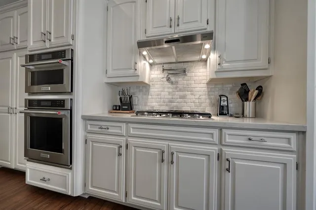 a kitchen with white cabinets and appliances