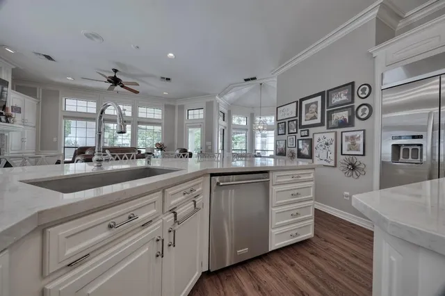 a kitchen with stainless steel appliances kitchen island granite countertop a sink cabinets and wooden floor