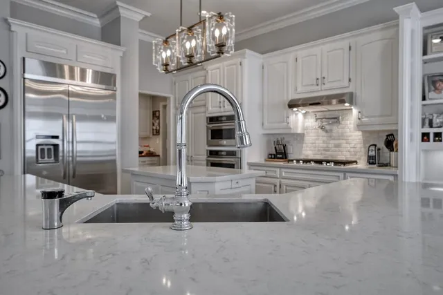 a view of a kitchen with stainless steel appliances granite countertop a stove oven and a refrigerator with white cabinets
