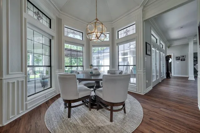 a dining room with wooden floor a chandelier a glass table and chairs