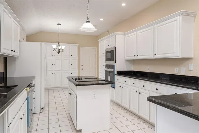 a kitchen with granite countertop a stove a sink and a refrigerator