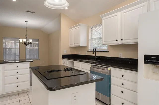 a kitchen with granite countertop a stove a sink and white cabinets