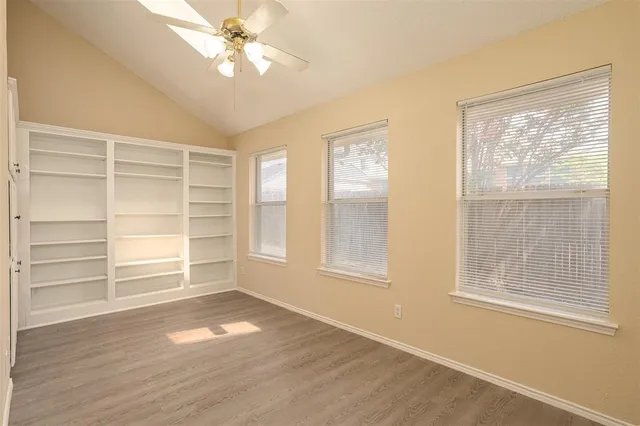 a view of an empty room with a window and wooden floor