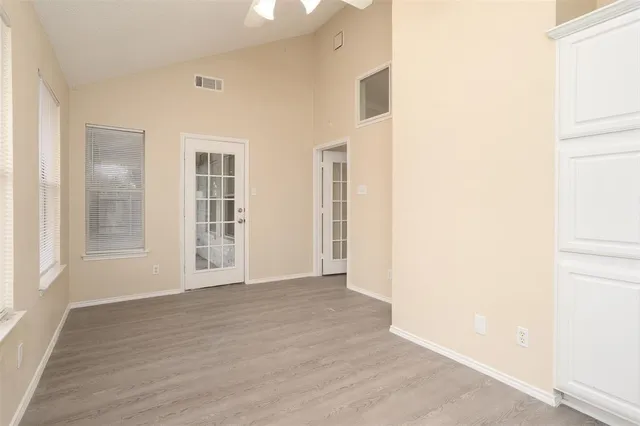 an empty room with wooden floor and windows
