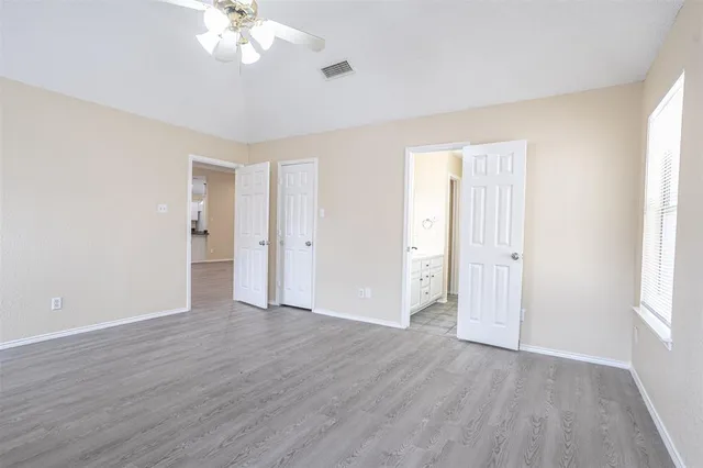 a view of an empty room with wooden floor and window