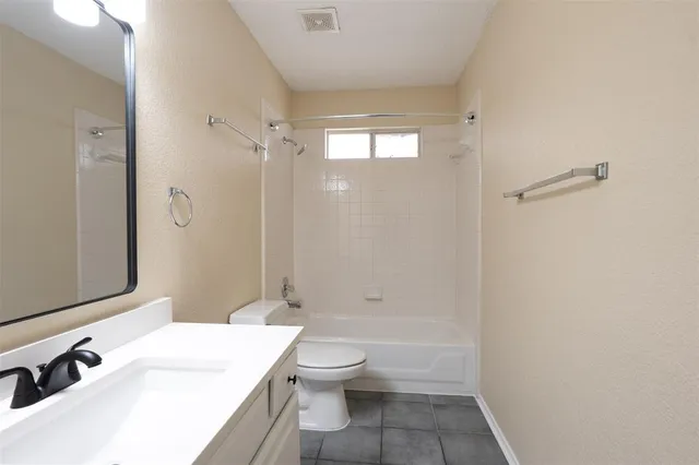 a bathroom with a granite countertop sink a toilet and shower