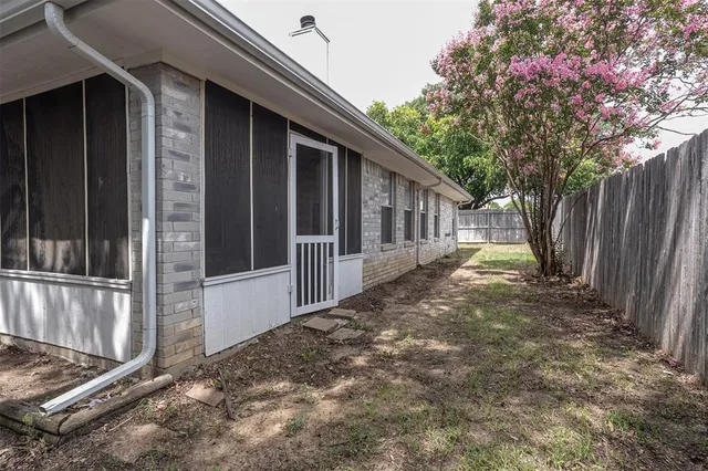 a view of a house with a small yard and wooden fence and a large tree