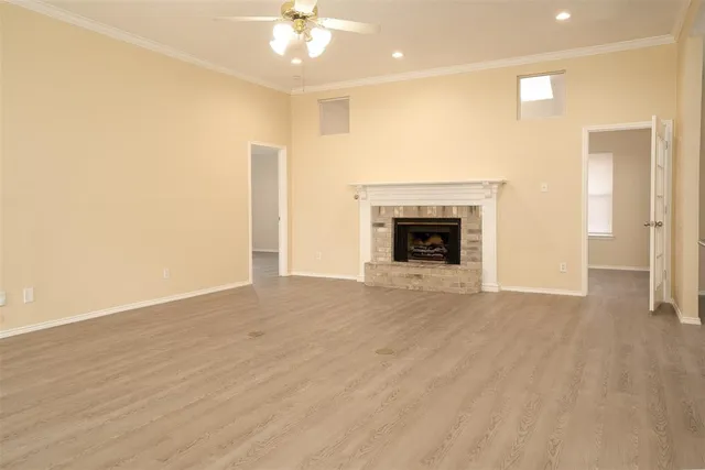 an empty room with wooden floor a ceiling fan and fireplace