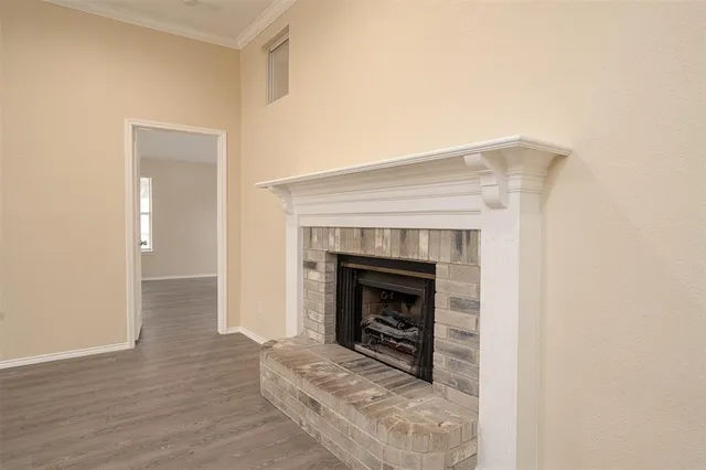 a view of an empty room with wooden floor and a fireplace