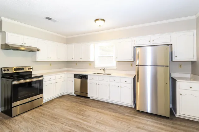 a kitchen with cabinets stainless steel appliances and wooden floor