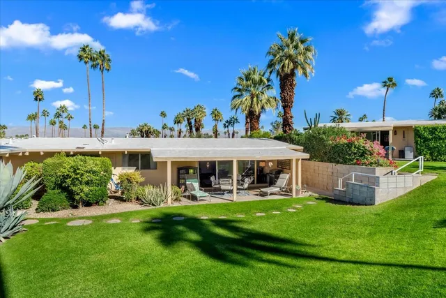 a view of a house with a yard chairs and table in the patio