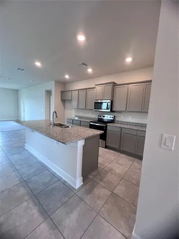 a large kitchen with kitchen island a stove a sink a counter top space and cabinets