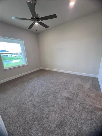 an empty room with a ceiling fan and window