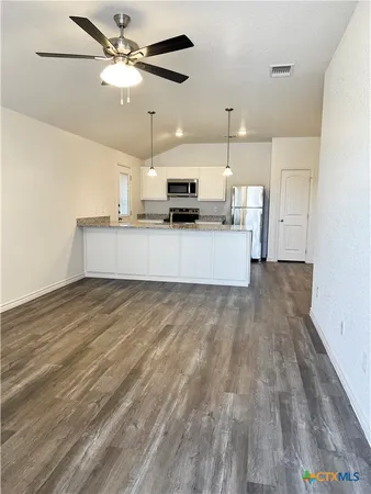 a view of a kitchen with kitchen island a counter top space wooden floor and a ceiling fan