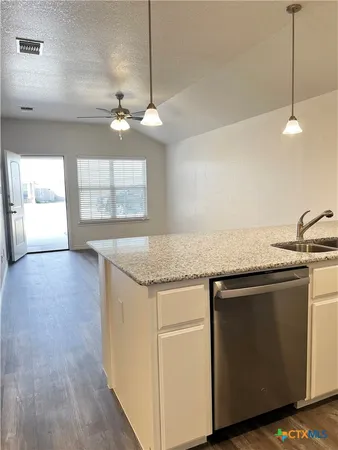 a kitchen with granite countertop a sink cabinets and wooden floor