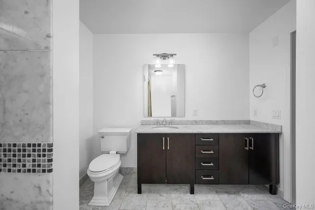 a bathroom with a granite countertop sink a toilet and a mirror