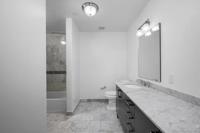 wooden floor with a granite countertop sink and a mirror