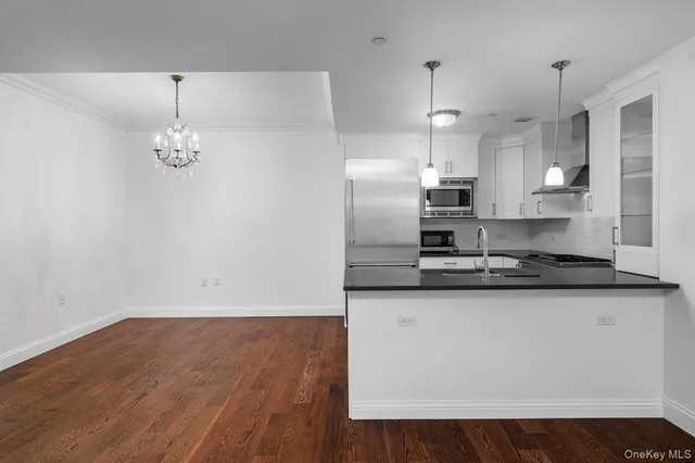 a kitchen with stainless steel appliances granite countertop a sink a refrigerator a stove a microwave and white cabinets with wooden floor