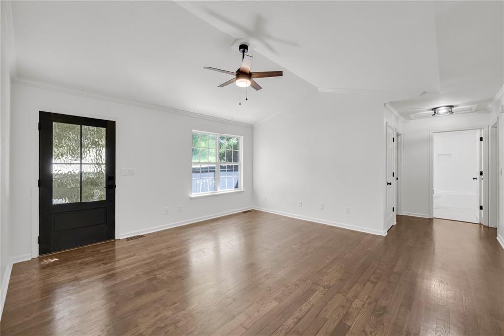 2941 Lake Hollow Road Gainesville, GA 30501 - Photo 8 of 53 an empty room with wooden floor chandelier fan and windows