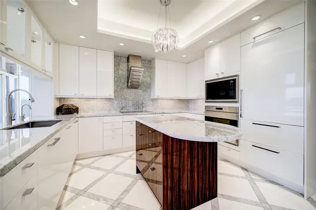 a kitchen with kitchen island granite countertop stainless steel appliances a sink dishwasher a refrigerator oven and white cabinets with wooden floor