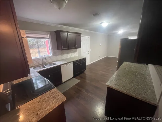 a kitchen with stainless steel appliances granite countertop a sink a stove and a wooden floors
