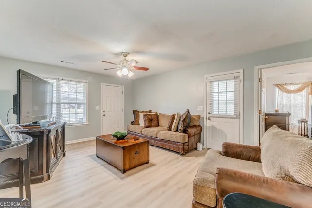 a living room with furniture a large window and a wooden floor
