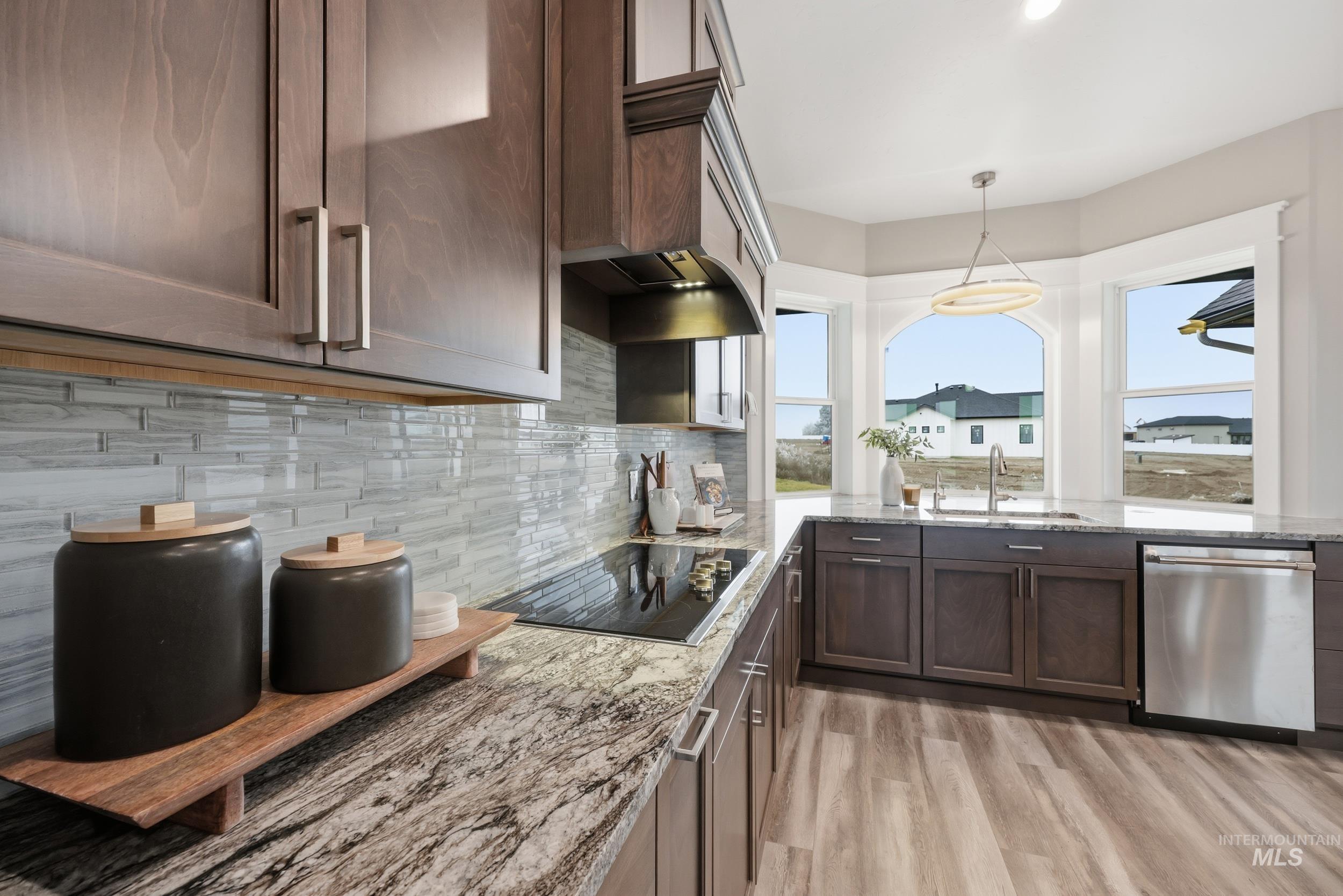 9264 Basin Kid Court Middleton, ID 83644 - Photo 12 of 50 Kitchen with dark brown cabinets, light stone countertops, dishwasher, black electric cooktop, and decorative backsplash