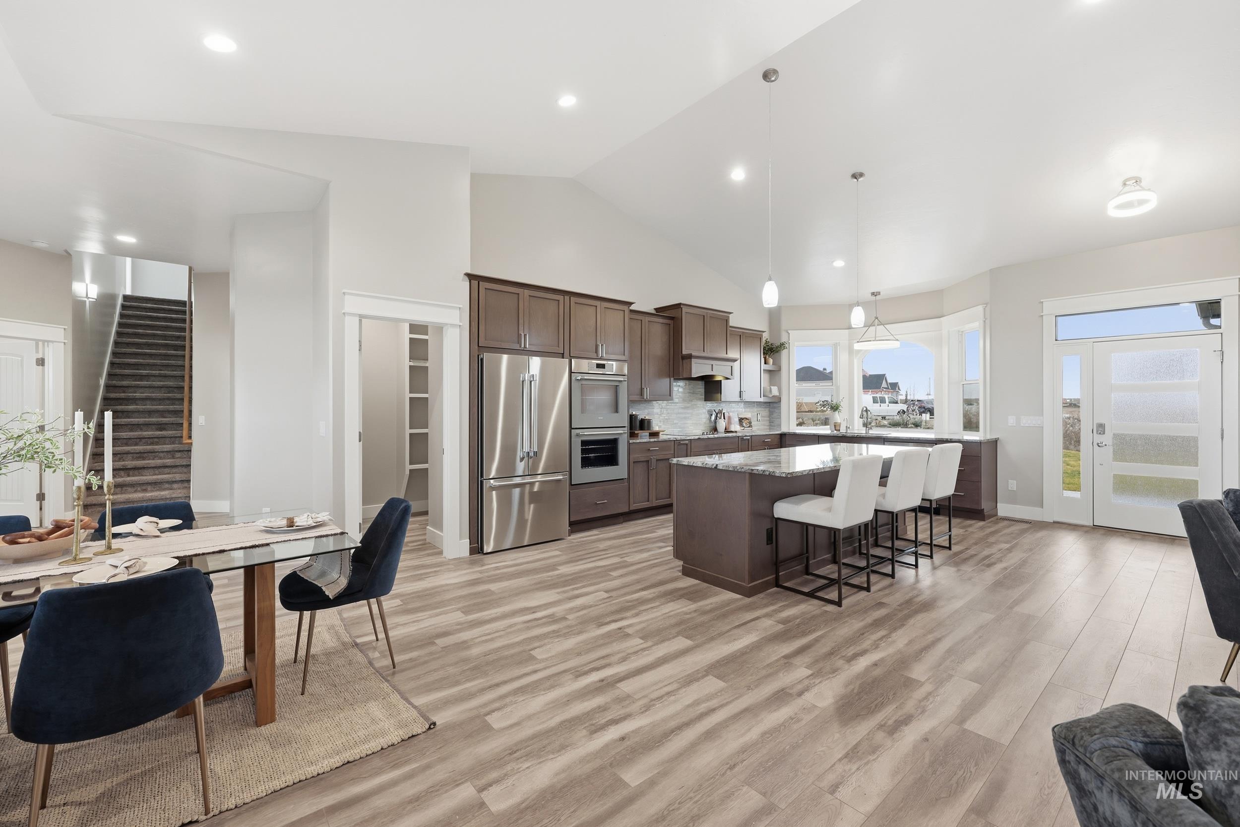 9264 Basin Kid Court Middleton, ID 83644 - Photo 50 of 50 Kitchen featuring appliances with stainless steel finishes, dark brown cabinetry, a breakfast bar area, open floor plan, and pendant lighting