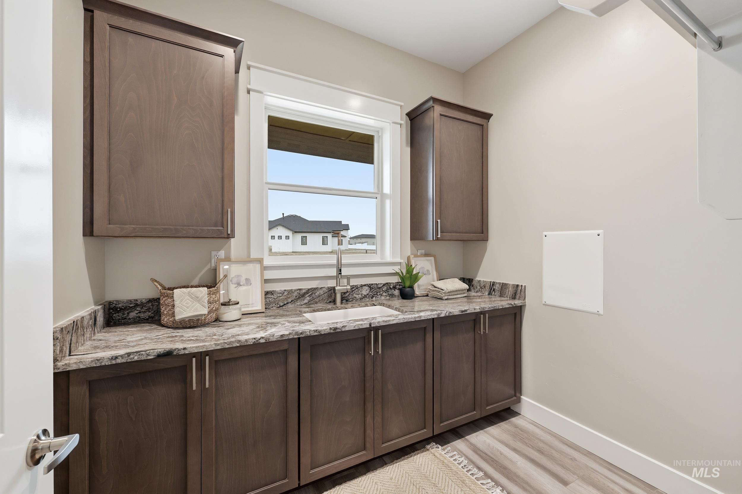 9264 Basin Kid Court Middleton, ID 83644 - Photo 24 of 50 Bar area featuring light stone countertops, dark brown cabinetry, and light wood finished floors