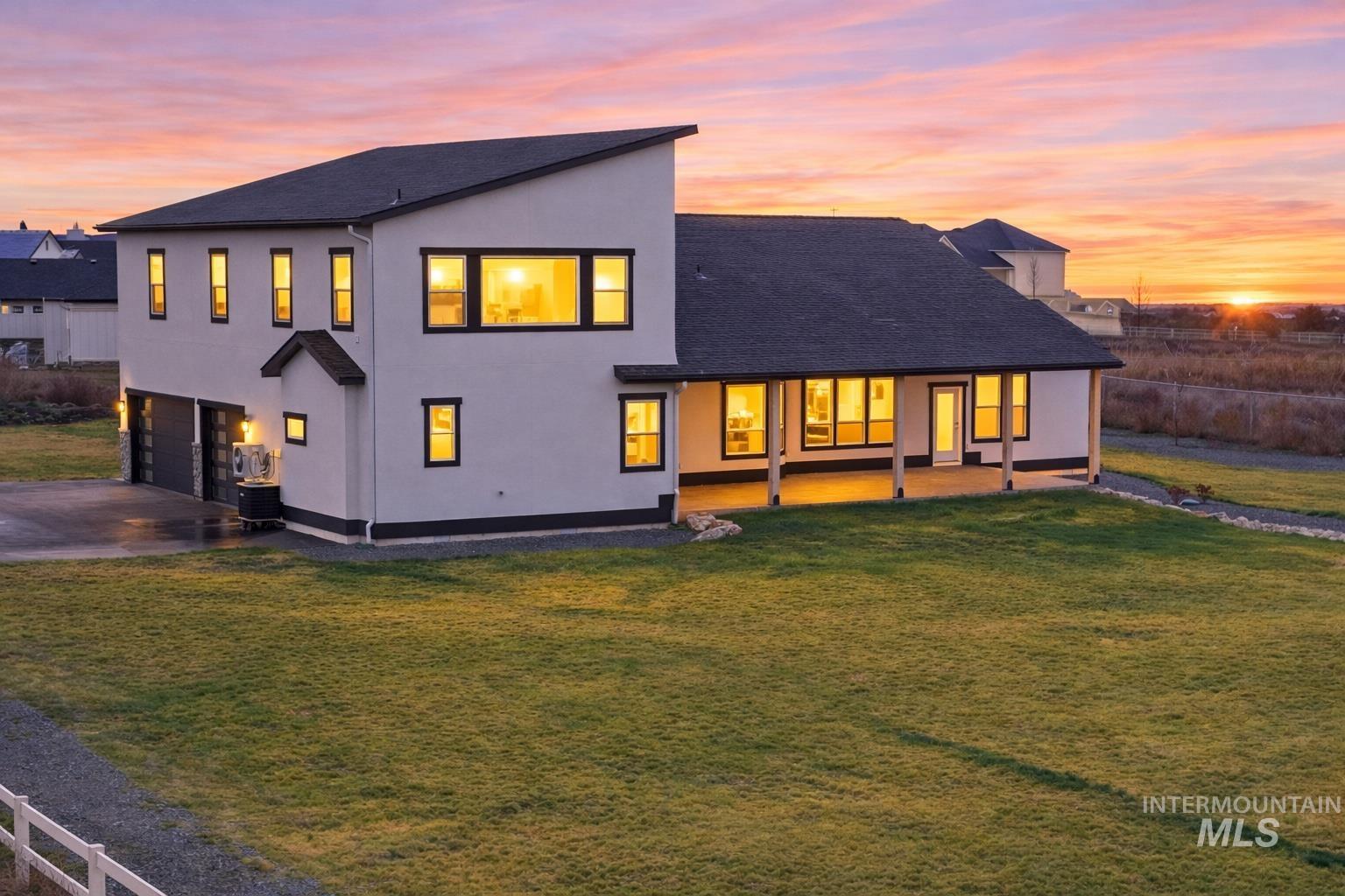 9264 Basin Kid Court Middleton, ID 83644 - Photo 28 of 50 Back of house with driveway, a lawn, an attached garage, stucco siding, and a patio area