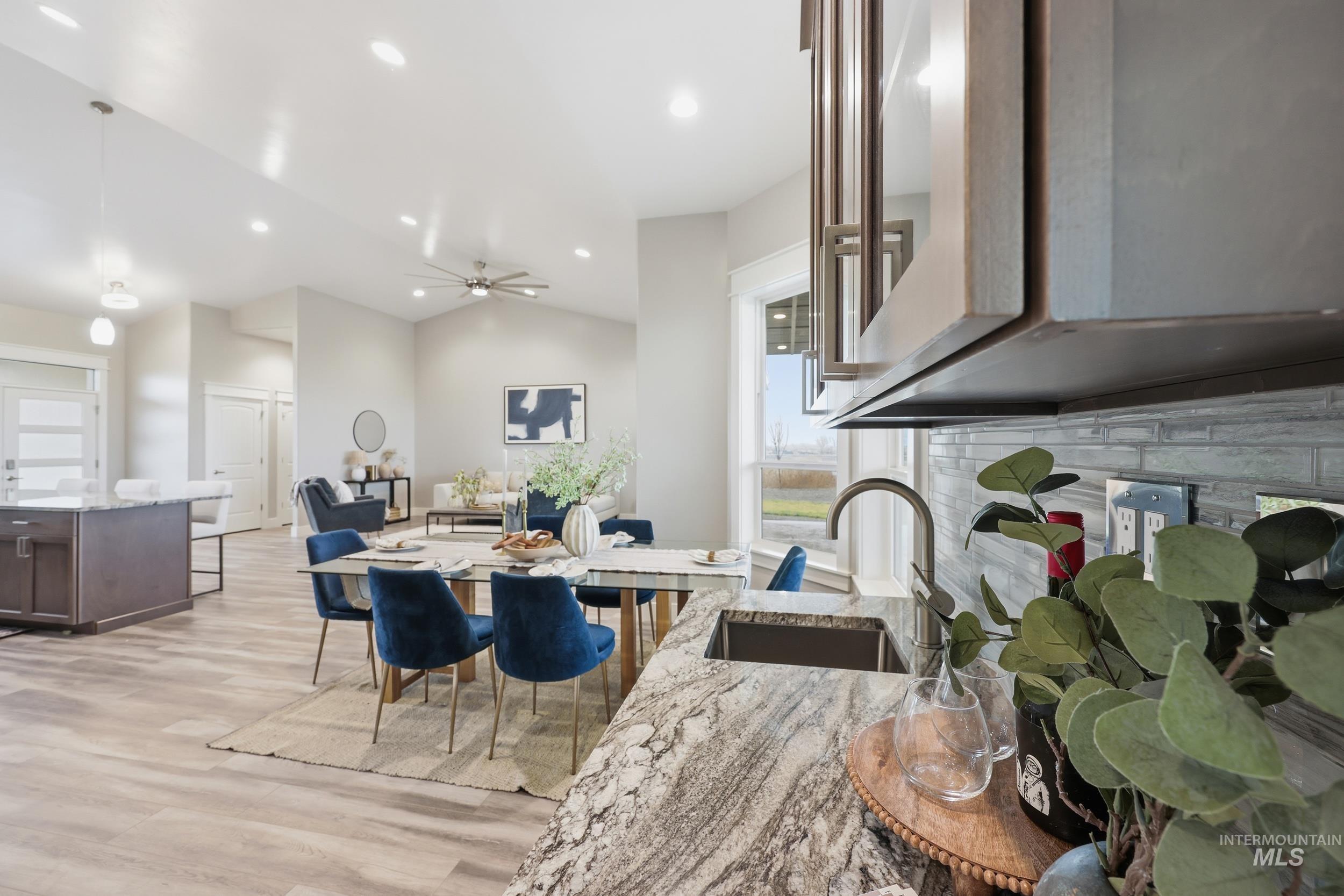 9264 Basin Kid Court Middleton, ID 83644 - Photo 6 of 50 Kitchen with light stone countertops, hanging light fixtures, dark brown cabinetry, light wood-style floors, and glass insert cabinets
